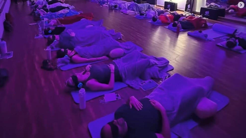 Group 9D Breathwork session with participants on mats wearing headphones and eye masks