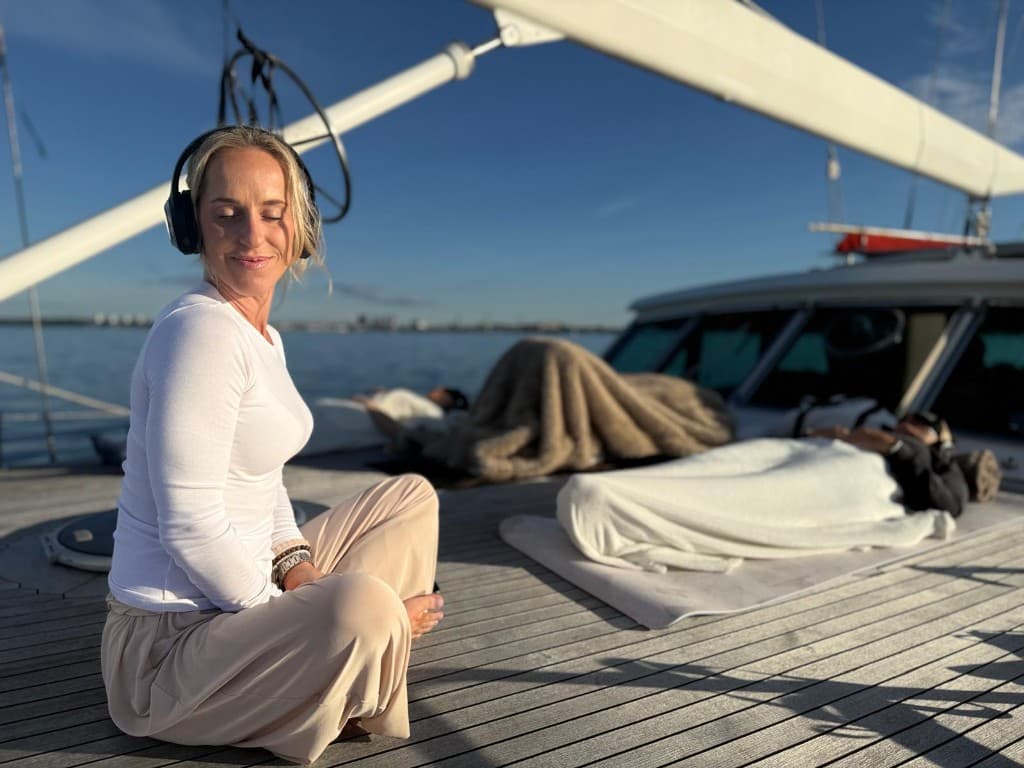 Liina Täht facilitating sunset breathwork on a sailboat deck with guests on mats